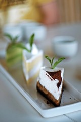Piece of cake white cream with blur cake background on table