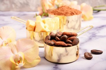Cocoa, cocoa butter and cocoa beans, chocolate in gold containers on a marble surface. Flat lay. Place for text.