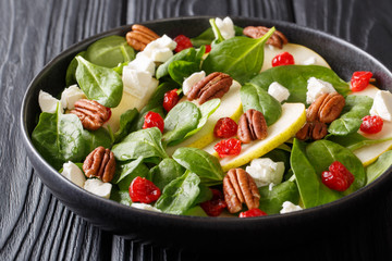 Spicy fruit salad with pears, baby spinach, pecans, feta cheese and cherries closeup on a plate. horizontal