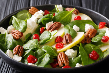 Autumn healthy salad of pears, baby spinach, pecans, feta cheese and dried cherries close-up. horizontal