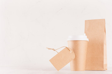 Coffee takeaway set mockup for brand - brown paper cup with blank label and craft bag on white wood board, copy space.