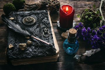 Spell book, magic potion and other various witchcraft accessories on the wizard table background.