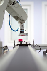 Focus on robotic arm's gripper. Industry 4.0 concept; artificial intelligence in smart factory. Robot picks up the product from automated car on the manufacturing line. Selective focus.
