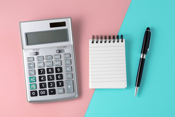Calculator and notepad on pastel pink and blue background