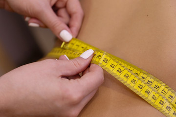 Doctor measuring waist of overweight woman before weight loss