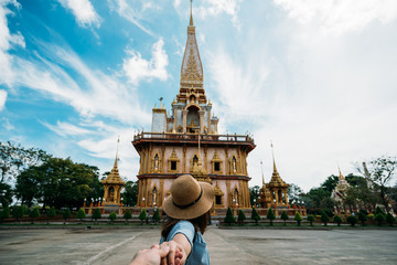 Young woman traveler holding hand man into beautiful pagoda in Wat Chalong or Chalong temple at Phuket town, Thailand. It's most popular thai temple in Phuket Thailand. © Travel man
