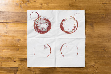 White napkin with wine trace on wooden background.