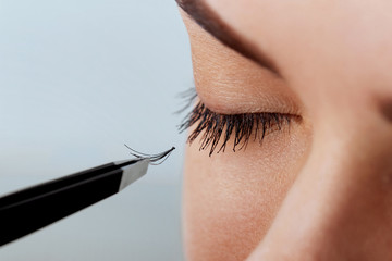 Beautiful Woman with long eyelashes in a beauty salon. Eyelash extension procedure. Lashes close...