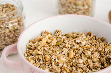 Homemade muesli in a bowl and glass jar, a bottle of milk on a white background