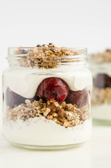 Homemade granola with cherry, yogurt in a glass jar