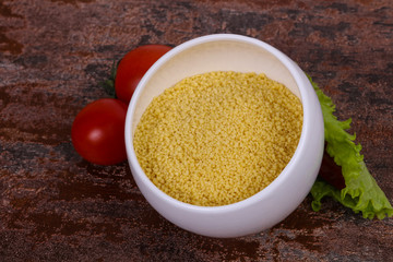 Raw couscous in the bowl served salad leaves, tomato and pepper
