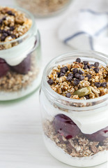 Homemade granola with cherry, yogurt in a glass jar