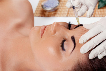 Obraz na płótnie Canvas Cosmetology,plastic surgery,beauty concept. Beautiful woman face and hand in glove with syringe making injection of botox near eyes, close-up. Portrait female receiving treatment of facial skin.