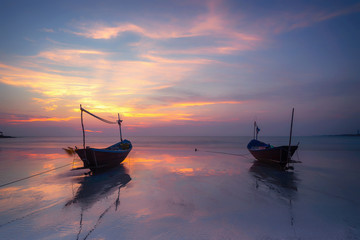 Wooden fishing boat on sea beach at sunset. © Natnan