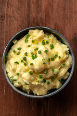 Pomme puree, a photo of a bowl of mashed potatoes with scallions, shot from the top on a dark rustic background with a place for text