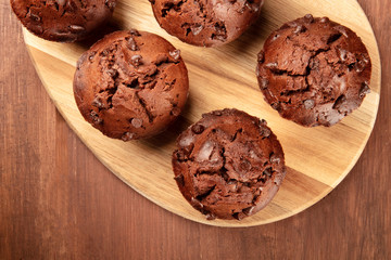 Chocolate muffins on a dark rustic wooden background, shot from above with a place for text