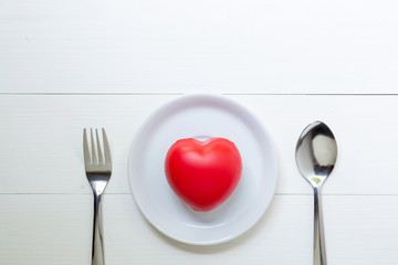 Red Heart with love and dish and spoon and fork on wooden background, 14 February Valentine day, on grunge white wood, celebration and holiday concept, top view.