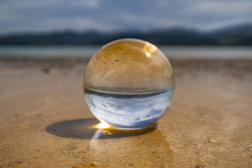 Fototapeta na wymiar lensball on the beach at Abel Tasman national pack, crystal glas ball at the beach of Abel Tasman coast track, lens ball photogaphy in New Zealand, great image at the beach