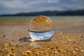 Fototapeta na wymiar lensball on the beach at Abel Tasman national pack, crystal glas ball at the beach of Abel Tasman coast track, lens ball photogaphy in New Zealand, great image at the beach