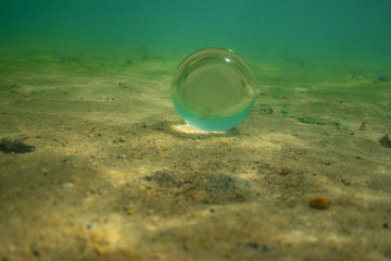 lens ball under water, crystal glas ball under water in Abel Tasman New Zealand, lens ball in the sand under water, under water photography 