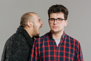A man angered screaming against his friend, his face deformed by the power of the cry, glasses,...