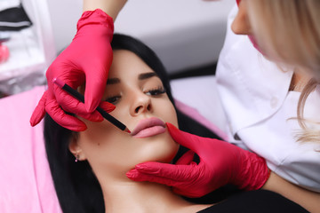 Cosmetologist making permanent makeup on woman's face