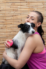 Stylish woman groomer combs mongrel dog on a background of reed mat