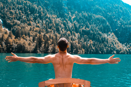 Young topless man in his paddle boat on the Koenigssee - Powered by Adobe
