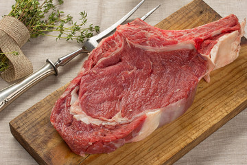 raw beef steak on wooden board with herbs.