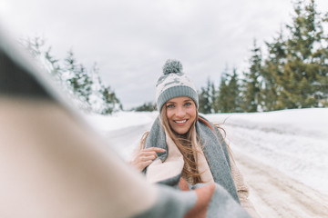 Beautiful blonde girl with comforter and hat posing in snow