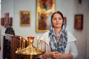 lifestyle woman lights candles in the Church, praying in front of the icon