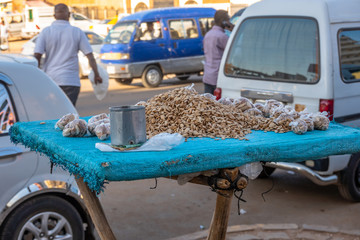 Sales table with a blue plastic tarpaulin and laid out sunflower seeds and a tin can with Sudanese banknotes placed under it at a market in Africa