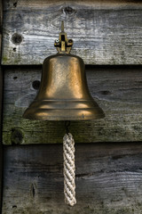 Obraz premium A close up of a small ships bell with a white lanyard hanging outside a house