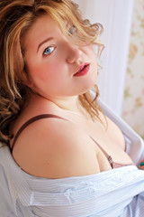 Sexy and beautiful plus size girl in lingerie and an open white shirt.