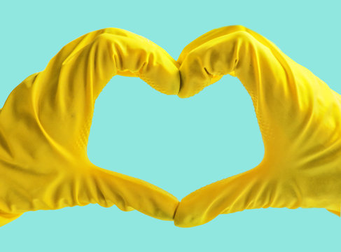 Getting started cleaning. Yellow rubber gloves for cleaning on blue background .General or regular cleanup. Commercial cleaning company. Copy space.Hands in yellow rubber gloves making heart shape