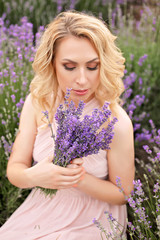 Pretty girl in a lavender field holding a bouquet of lavender.
