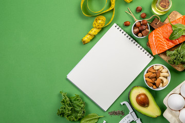 Keto diet concept - salmon, avocado, eggs, nuts and seeds, bright green background, top view