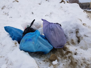 Garbage and garbage bags scattered on snow in winter