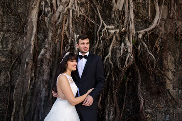 Handsome groom and young beautiful woman posing in front of graffiti wall