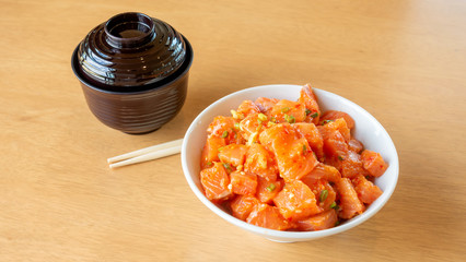 Fresh spicy salmon and rice on a wooden table.