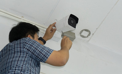 Technician Fixing Camera On Wall With Screwdriver