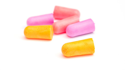 Yellow, violet and pink earplugs on a white background.