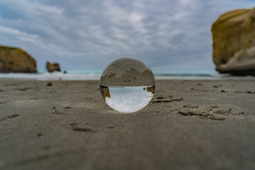 crystal ball on tunnel beach in New Zealand with rocks in the background, lansball on the beach, amazing tunnel beach in New Zealand with a crystal ball in the foreground,