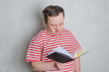 Man with down syndrome holding and reading a book.Concept of education for special people