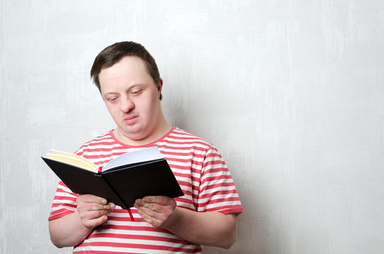 Young Man With Down Syndrome Reading A Book