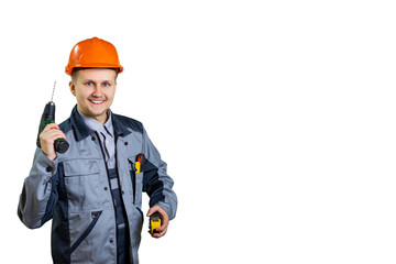 A handsome builder and engineer in a helmet with a drill and ruler, smiling, ready to make for you a quality repair of anything. The concept of repair and construction. isolated.