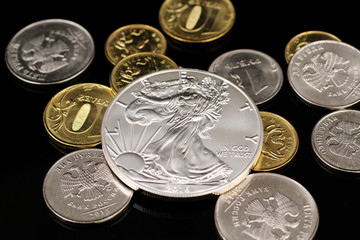 A macro image of a American silver coin on a black reflective background with Russian Federation coins