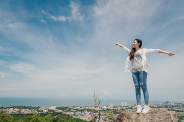 Portrait of carefree happy asian woman standing on top of mountain edge cliff enjoying  on her face. Freedom; Lifestyle; Enjoyment; Relaxing in mountains at Huahin in Thailand.