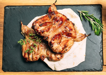 Grilled quails on wooden plate