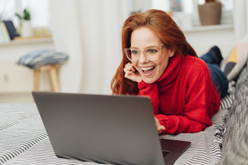 Red haired girl laying on couch with laptop